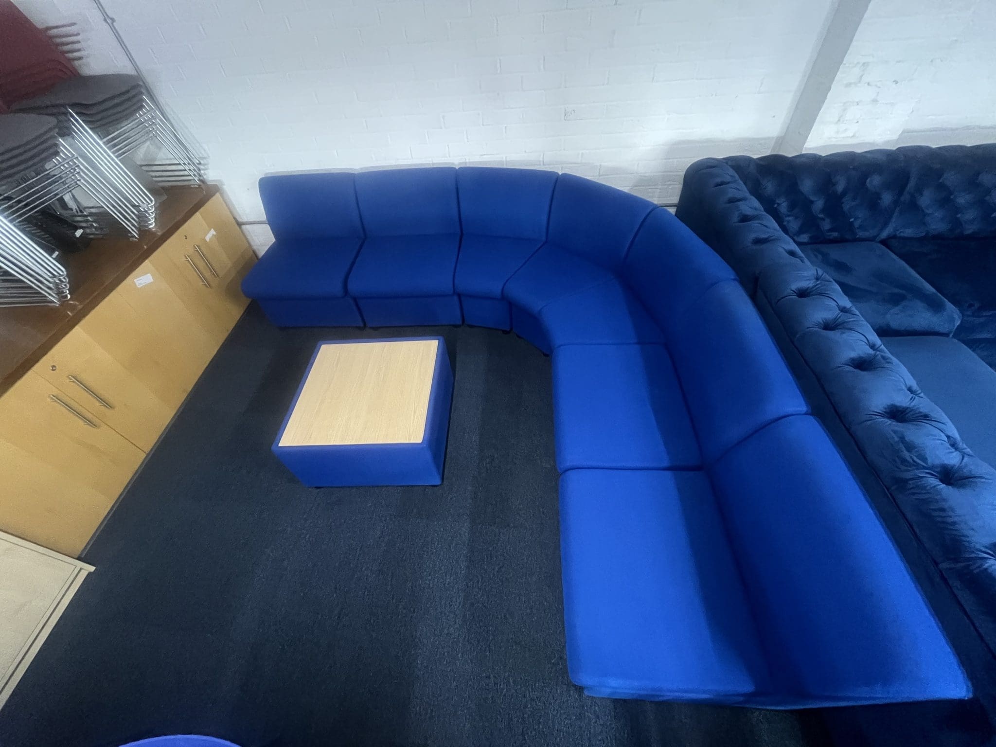 A blue modular corner settee with a square wooden coffee table in the center, top view