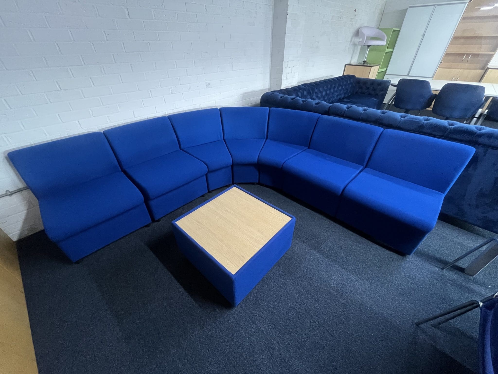 A blue modular corner settee with a square wooden coffee table in the center, front view